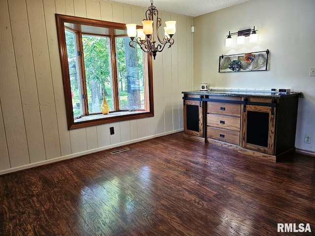 12862 Winnebago Dr, Plainview, IL 62685 - unfurnished dining area featuring dark wood-style floors, a chandelier, wooden walls, baseboards, and a textured ceiling