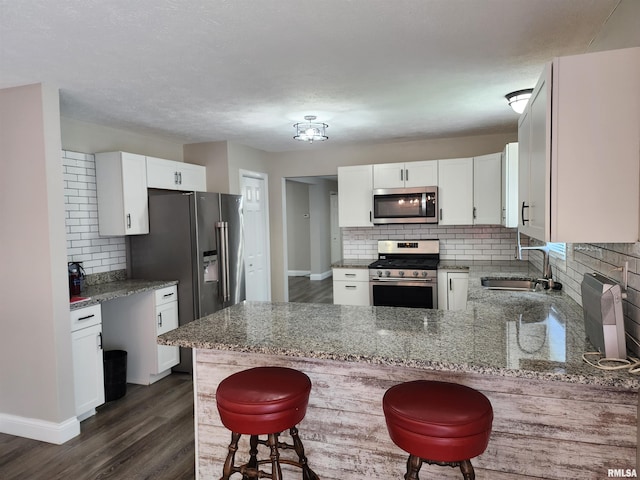 208 Elm St, Dawson, IL 62520 - kitchen featuring appliances with stainless steel finishes, a sink, decorative backsplash, a peninsula, and stone counters