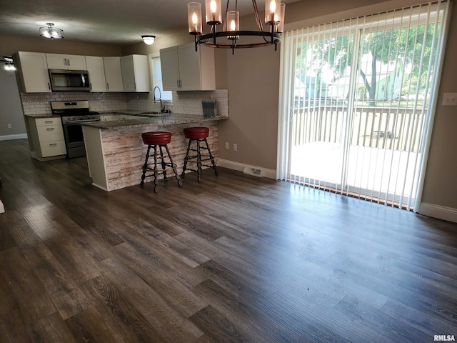 208 Elm St, Dawson, IL 62520 - kitchen with appliances with stainless steel finishes, a chandelier, decorative backsplash, a sink, and baseboards