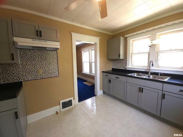 2240 Holmes Ave, Springfield, IL 62704 - kitchen featuring under cabinet range hood, ornamental molding, plenty of natural light, dark countertops, and backsplash