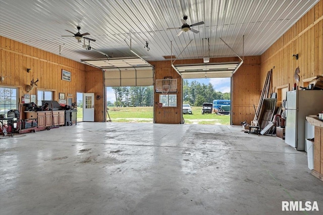 14455 E Dutch Henry Rd, Lewistown, IL 61542 - garage with freestanding refrigerator, ceiling fan, wood walls, and a garage door opener