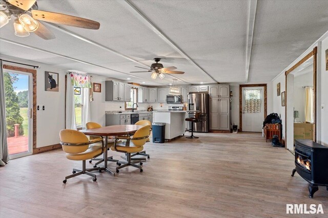 14455 E Dutch Henry Rd, Lewistown, IL 61542 - dining space featuring ceiling fan, a textured ceiling, a wood stove, light wood-style flooring, and baseboards