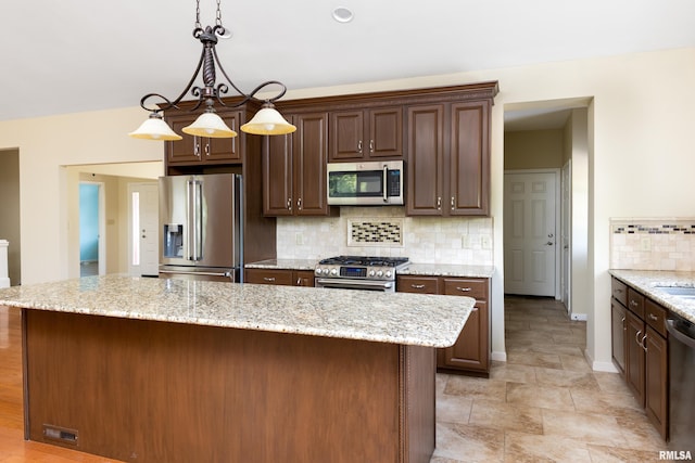 6718 Shadow Ln, Quincy, IL 62305 - kitchen featuring appliances with stainless steel finishes, decorative backsplash, pendant lighting, a center island, and light stone finish flooring
