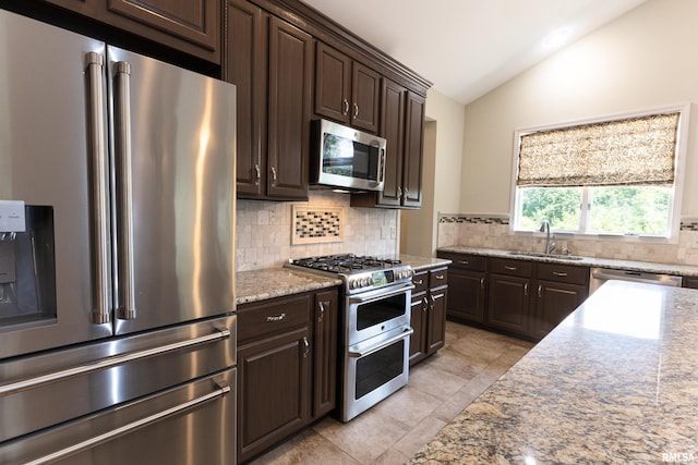 6718 Shadow Ln, Quincy, IL 62305 - kitchen with appliances with stainless steel finishes, lofted ceiling, decorative backsplash, dark brown cabinetry, and light stone countertops