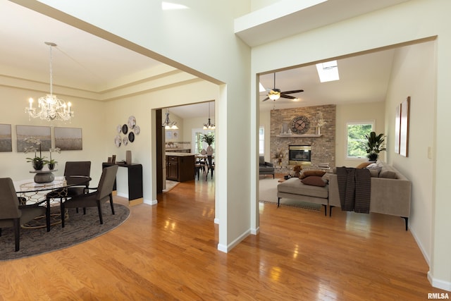 6718 Shadow Ln, Quincy, IL 62305 - dining area featuring a chandelier, light wood-style flooring, a brick fireplace, ceiling fan, and a high ceiling