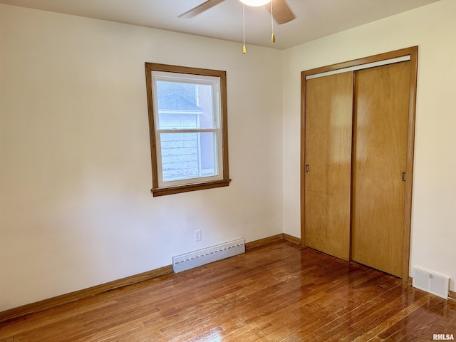 465 Fifer St, Galesburg, IL 61401 - unfurnished bedroom with a baseboard heating unit, wood-type flooring, a closet, and a ceiling fan