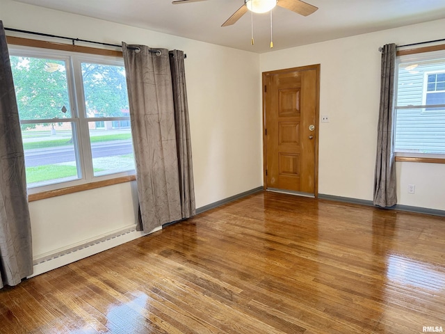 465 Fifer St, Galesburg, IL 61401 - spare room featuring wood finished floors, a baseboard radiator, a ceiling fan, and healthy amount of natural light