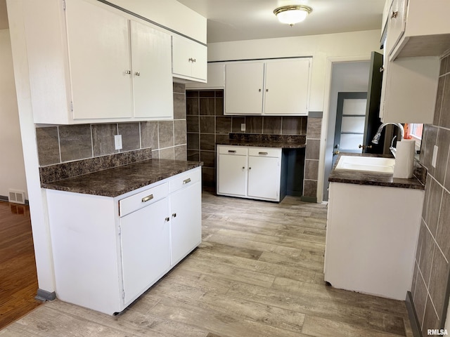 465 Fifer St, Galesburg, IL 61401 - kitchen with light wood-style flooring, tile walls, white cabinets, dark countertops, and backsplash