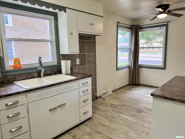 465 Fifer St, Galesburg, IL 61401 - kitchen featuring dark countertops, light wood finished floors, white cabinets, and tasteful backsplash