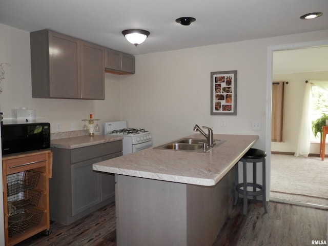 104 Henderson Rd, Knoxville, IL 61448 - kitchen featuring black microwave, white range with gas stovetop, a breakfast bar, gray cabinetry, and dark wood finished floors