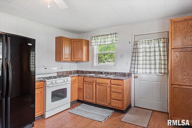 402 Linkins Ave, Tovey, IL 62570 - kitchen with freestanding refrigerator, white range with gas cooktop, crown molding, dark countertops, and light wood-style flooring