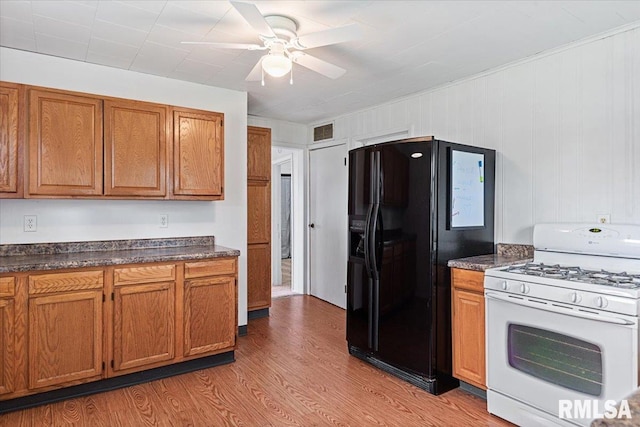 402 Linkins Ave, Tovey, IL 62570 - kitchen with gas range gas stove, black fridge, light wood-style flooring, and dark countertops