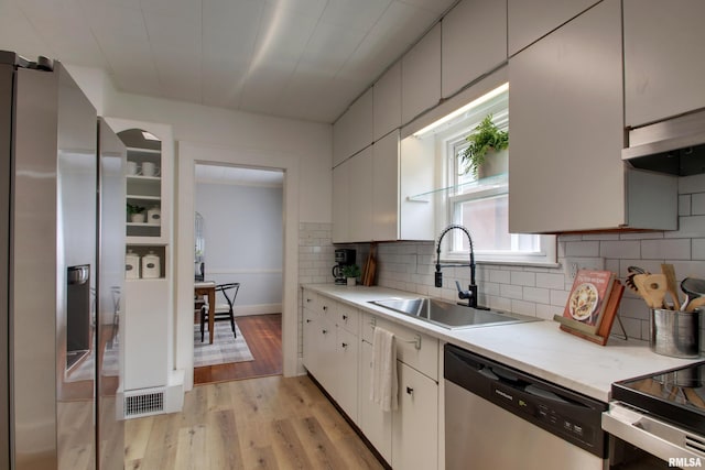 2204 Spring St, Quincy, IL 62301 - kitchen featuring stainless steel appliances, light countertops, light wood finished floors, and tasteful backsplash