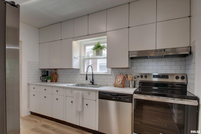 2204 Spring St, Quincy, IL 62301 - kitchen featuring stainless steel appliances, under cabinet range hood, light wood-type flooring, light countertops, and tasteful backsplash