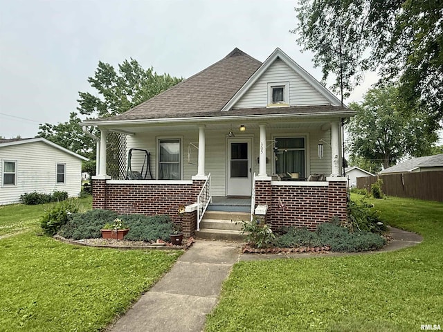 305 N Harshbarger St, Abingdon, IL 61410 - bungalow-style house with a front yard, a porch, brick siding, and roof with shingles