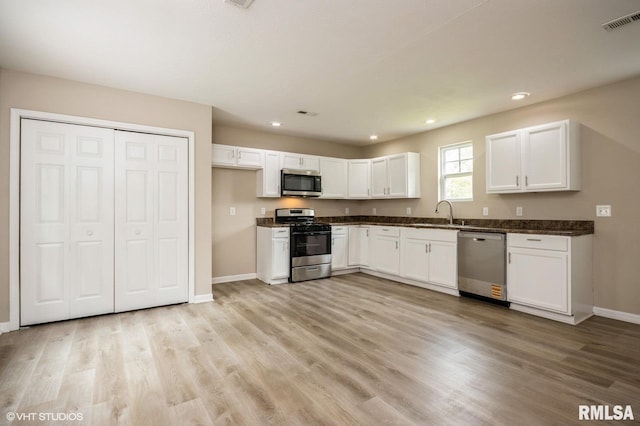 713 S Jackson St, Litchfield, IL 62056 - kitchen featuring stainless steel appliances, dark countertops, white cabinets, light wood-style floors, and recessed lighting