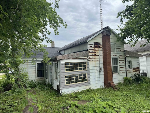 219 5th St, Lincoln, IL 62656 - view of property exterior with a chimney and a central air condition unit