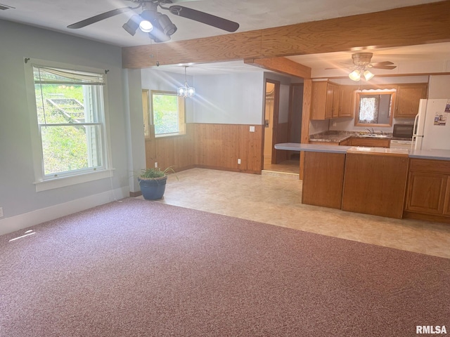 220 E Adams St, Petersburg, IL 62675 - kitchen with freestanding refrigerator, ceiling fan, wood walls, brown cabinets, and light countertops