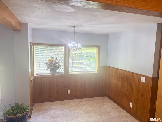 220 E Adams St, Petersburg, IL 62675 - spare room featuring wooden walls, wainscoting, a chandelier, light flooring, and a textured ceiling