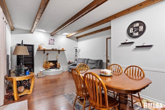 838 Hackberry Rd, Chatham, IL 62629 - dining space featuring beamed ceiling, wood-type flooring, a fireplace, a wainscoted wall, and brick wall