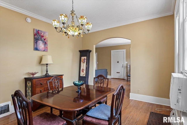 2141 S 4th St, Springfield, IL 62703 - dining space with arched walkways, wood finished floors, a chandelier, ornamental molding, and a textured ceiling