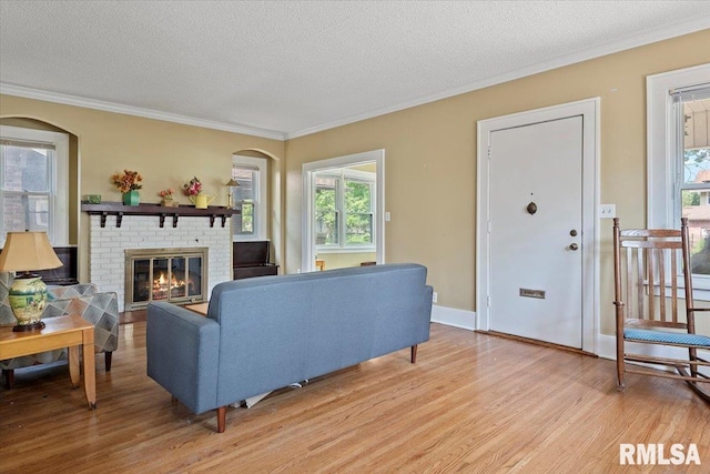 2141 S 4th St, Springfield, IL 62703 - living room with light wood-style flooring, crown molding, plenty of natural light, a textured ceiling, and a brick fireplace