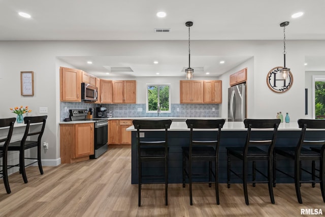 10 The Elms Ln, Springfield, IL 62712 - kitchen featuring stainless steel appliances, light countertops, light wood-style flooring, tasteful backsplash, and plenty of natural light