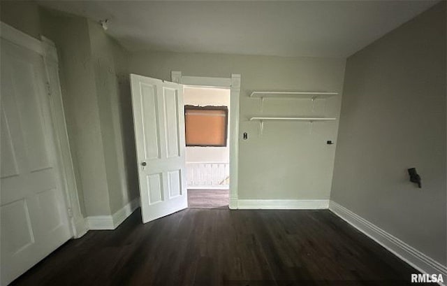 518 E 4th Ave, Monmouth, IL 61462 - unfurnished bedroom featuring baseboards and dark wood-type flooring
