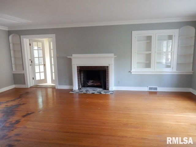 635 S Seigel St, Decatur, IL 62522 - unfurnished living room with wood finished floors, a brick fireplace, crown molding, and built in shelves