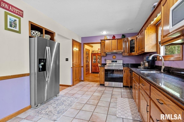 3713 Tyler Ct, Springfield, IL 62711 - kitchen featuring stainless steel appliances, brown cabinets, under cabinet range hood, light tile patterned floors, and dark stone counters