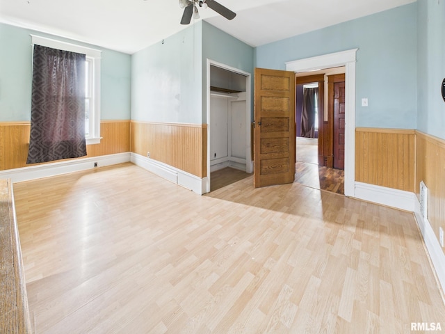 222 N Lewis St, Blue Mound, IL 62513 - unfurnished bedroom featuring a wainscoted wall, wood finished floors, a closet, wood walls, and a ceiling fan