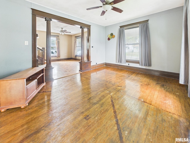 222 N Lewis St, Blue Mound, IL 62513 - unfurnished room with decorative columns, ceiling fan, wood-type flooring, and healthy amount of natural light