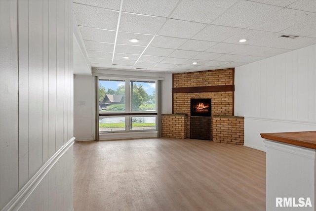 308 Elm Ln, Petersburg, IL 62675 - unfurnished living room featuring wood finished floors, a fireplace, a drop ceiling, and wooden walls