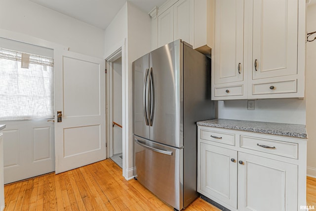 712 N Kickapoo St, Lincoln, IL 62656 - kitchen featuring freestanding refrigerator, light wood-style floors, white cabinetry, and light stone counters