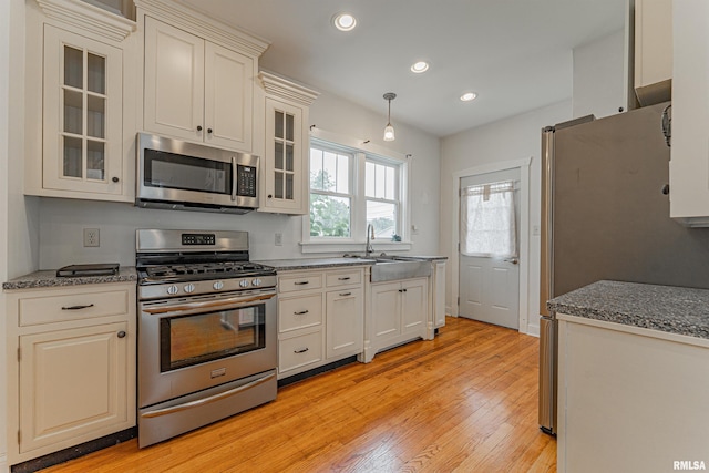 712 N Kickapoo St, Lincoln, IL 62656 - kitchen featuring stainless steel appliances, recessed lighting, light wood-type flooring, glass insert cabinets, and pendant lighting