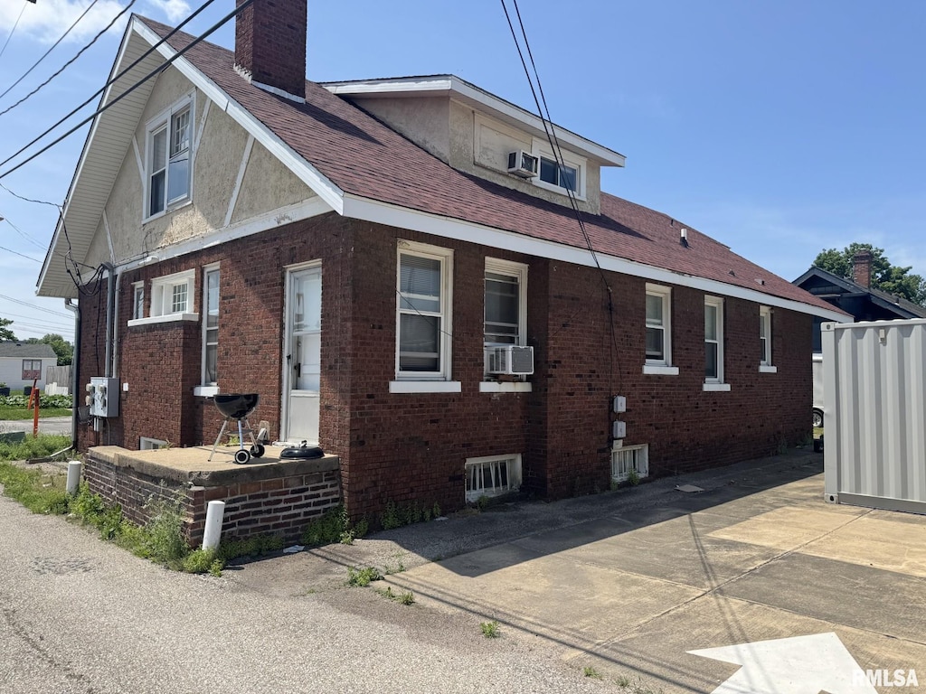 515 E Vine St, Springfield, IL 62704 - view of home's exterior featuring a chimney, brick siding, cooling unit, and roof with shingles