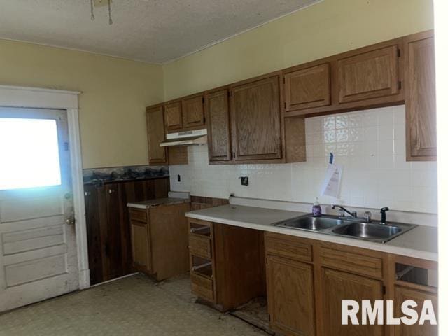 2541 S 10th St, Springfield, IL 62703 - kitchen with under cabinet range hood, brown cabinets, a textured ceiling, light floors, and backsplash