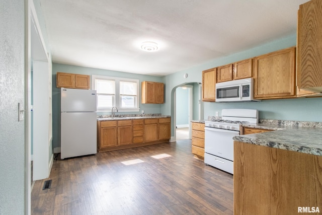 100 N Austin Ave, Abingdon, IL 61410 - kitchen featuring white appliances, arched walkways, dark wood finished floors, and brown cabinets