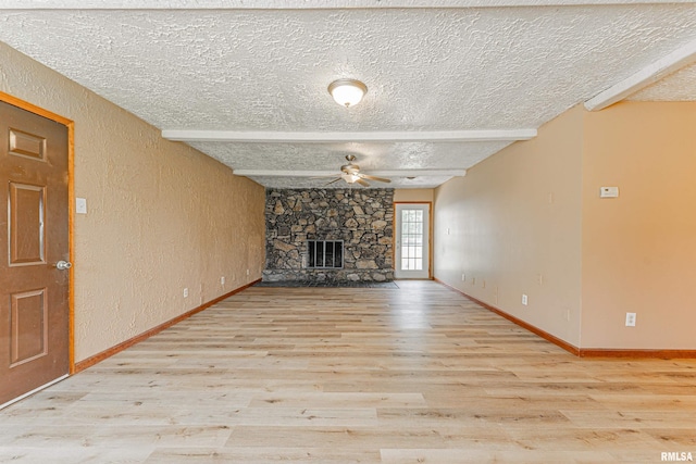 205 E Pine St, Broadwell, IL 62634 - unfurnished living room with a textured ceiling, a ceiling fan, wood finished floors, a textured wall, and a fireplace