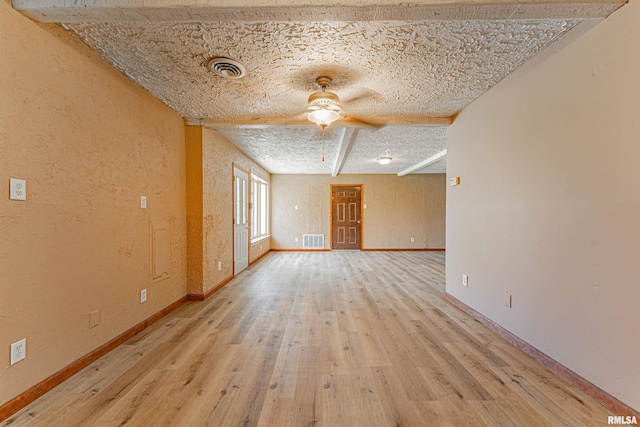 205 E Pine St, Broadwell, IL 62634 - spare room featuring wood finished floors, a ceiling fan, beamed ceiling, a textured wall, and a textured ceiling