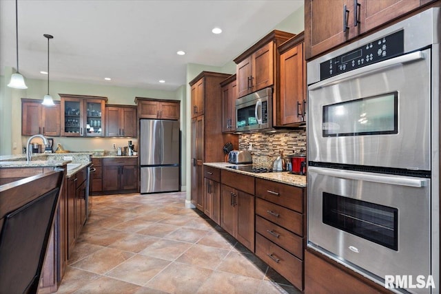 5408 Cromwell Pl, Springfield, IL 62711 - kitchen with appliances with stainless steel finishes, backsplash, light stone countertops, glass insert cabinets, and pendant lighting