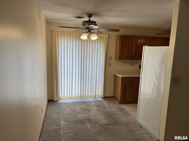 100 E Heights Ave, Taylorville, IL 62568 - kitchen featuring freestanding refrigerator, a ceiling fan, light carpet, a textured ceiling, and brown cabinetry