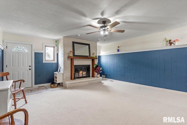 240 Mine Ave, Girard, IL 62640 - unfurnished living room with a textured ceiling, ceiling fan, a fireplace, carpet, and wainscoting