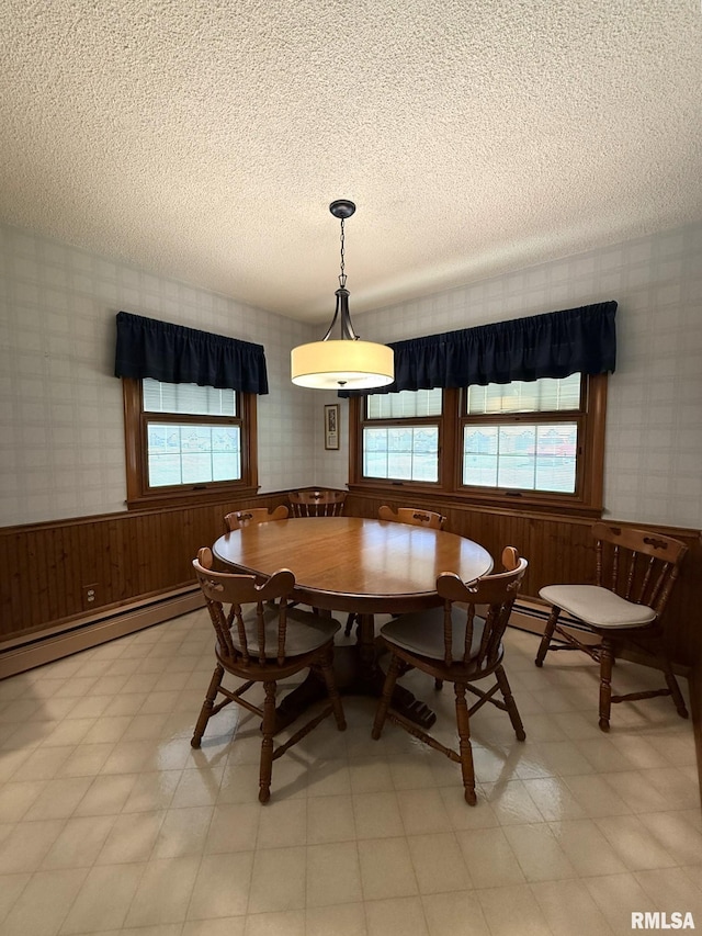 597 Walnut St, Knoxville, IL 61448 - dining area with wallpapered walls, a textured ceiling, light flooring, a wainscoted wall, and baseboard heating