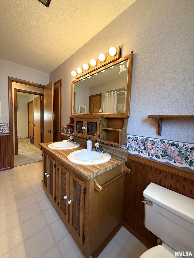 597 Walnut St, Knoxville, IL 61448 - full bath featuring tile patterned floors, double vanity, a wainscoted wall, and a textured ceiling