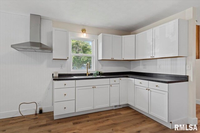707 N Adams St, Lincoln, IL 62656 - kitchen featuring wall chimney range hood, wood finished floors, dark countertops, and white cabinets