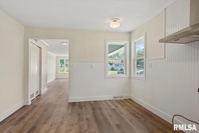 707 N Adams St, Lincoln, IL 62656 - unfurnished dining area with light wood-type flooring and a wainscoted wall