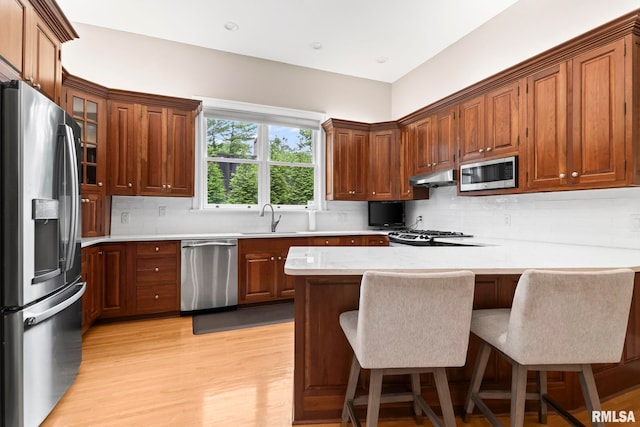 1125 Williams Blvd, Springfield, IL 62704 - kitchen with appliances with stainless steel finishes, under cabinet range hood, a peninsula, light countertops, and light wood-style floors