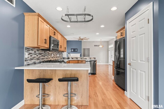 401 Cherry Cir, Williamsville, IL 62693 - kitchen featuring a peninsula, stainless steel appliances, light countertops, backsplash, and light wood finished floors