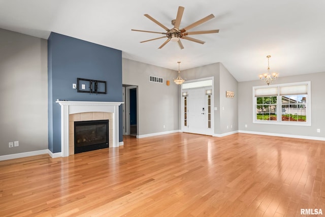 401 Cherry Cir, Williamsville, IL 62693 - unfurnished living room featuring a tiled fireplace, a chandelier, a ceiling fan, and light wood-type flooring
